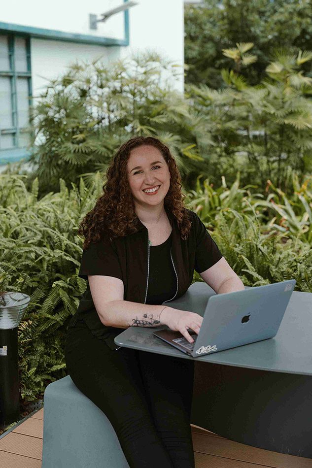 Christy Walowit, sitting at a table, focused on her laptop, with a cozy atmosphere around her.